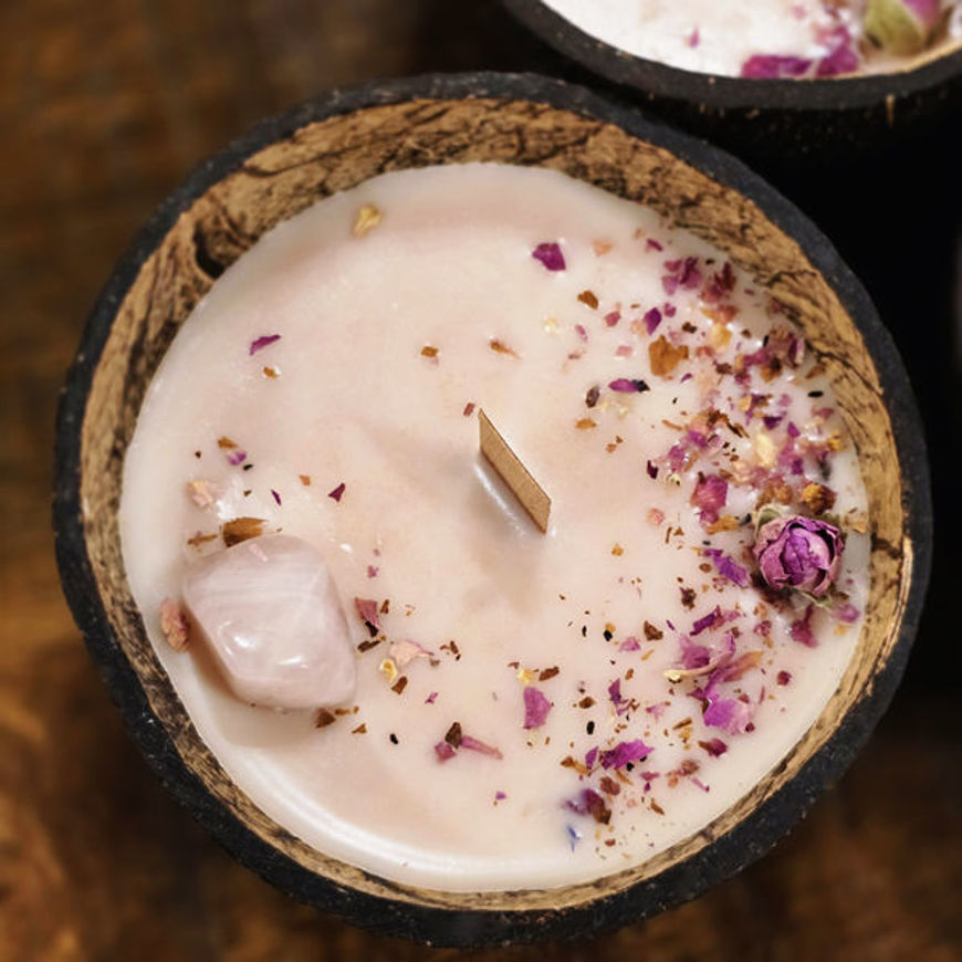 Natural coconut-shell candle with wooden wick, scented with rose and benzoin, styled as a soft pink “Love” aromatherapy candle.
