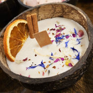 Coconut-shell candle with wooden wick, scented with cinnamon and orange, featured as the “Joy & Prosperity” aromatherapy candle.